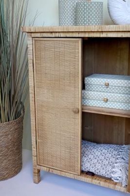 Rattan cabinet with double doors, woven finish, natural tone, raised legs and round wooden handles for storage.