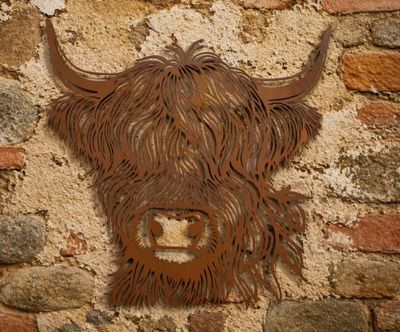 Rustic metal wall art of a Highland cow with flowing hair, mounted on a textured brick wall, adding countryside charm,