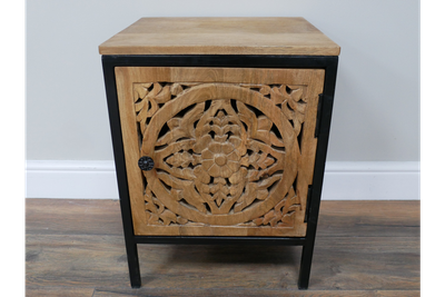Hand-carved wooden bedside cabinet with floral door design, natural wood finish and black frame.