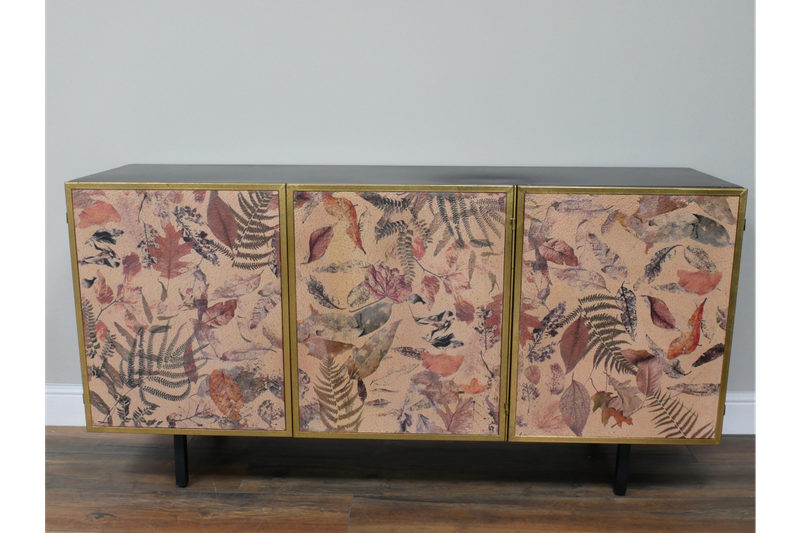 Botanical three-door sideboard featuring leaf and fern artwork, gold trim and slim black legs for elegant storage.