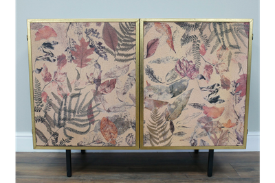 Botanical cabinet featuring leaf and fern artwork, gold trim and slim black legs for elegant storage.