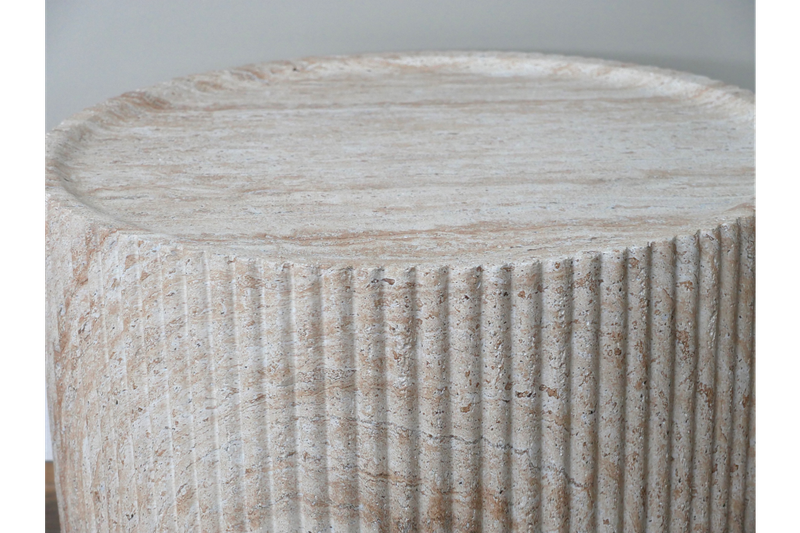Round stone-effect coffee table with ribbed detailing, natural textured finish and a contemporary sculptural design.