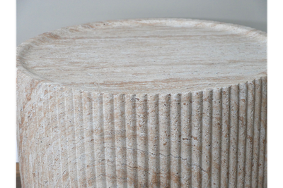 Round stone-effect coffee table with ribbed detailing, natural textured finish and a contemporary sculptural design.