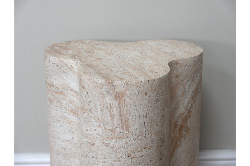 Travertine-effect side table with sculptural pillar base and organic shape in warm cream and natural stone tones.