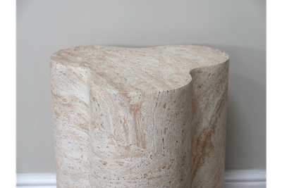 Travertine-effect side table with sculptural pillar base and organic shape in warm cream and natural stone tones.
