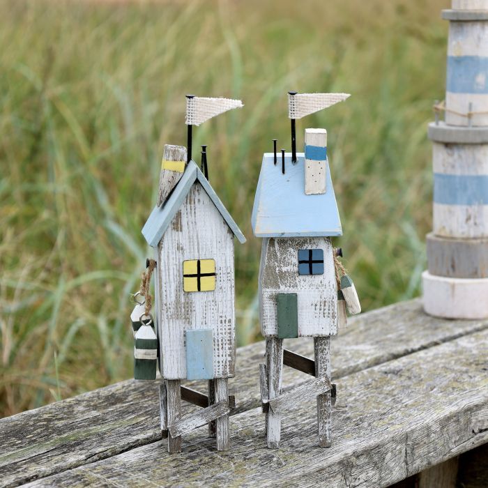 Set of two rustic wooden beach houses on stilts with pastel blue roofs, nautical details and weathered finish.