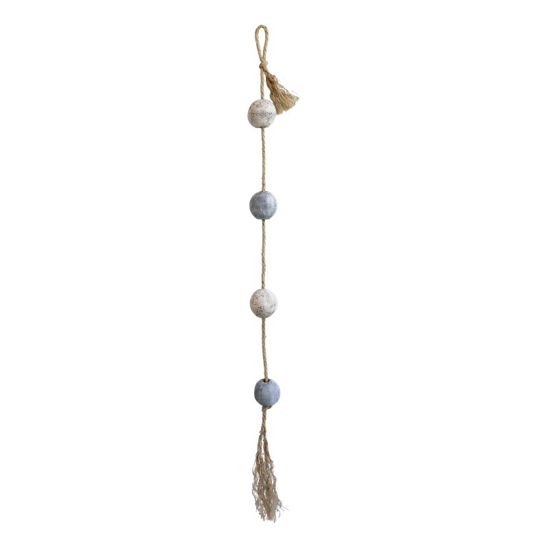 Weathered blue and white wooden fishing floats threaded on natural rope with tassels, styled on a rustic surface.