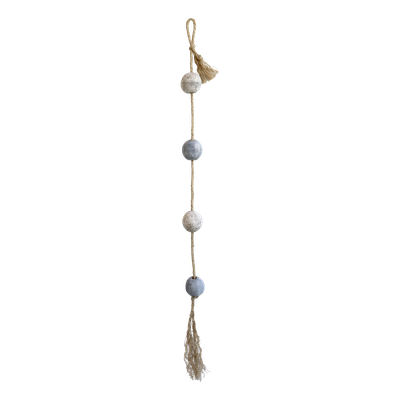 Weathered blue and white wooden fishing floats threaded on natural rope with tassels, styled on a rustic surface.