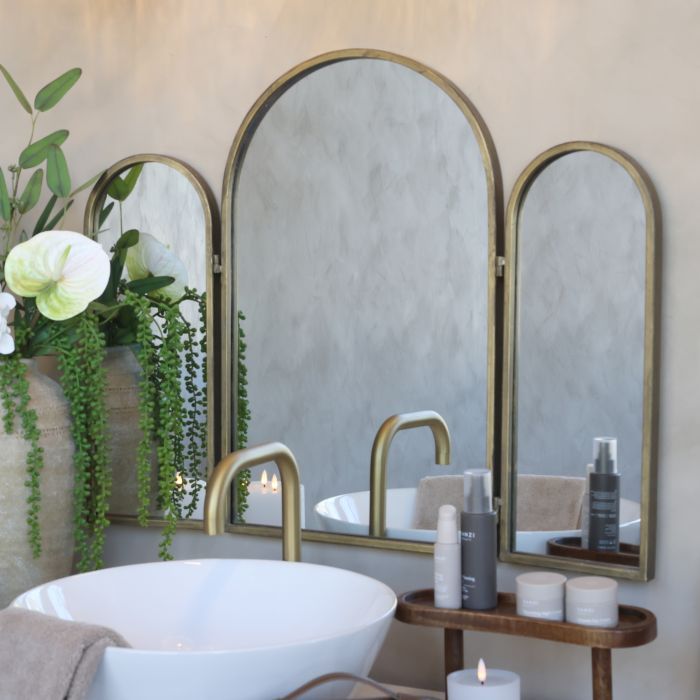 Tri fold arched mirror with an aged metal frame and hinged side panels, perfect for dressing tables or mantel displays.