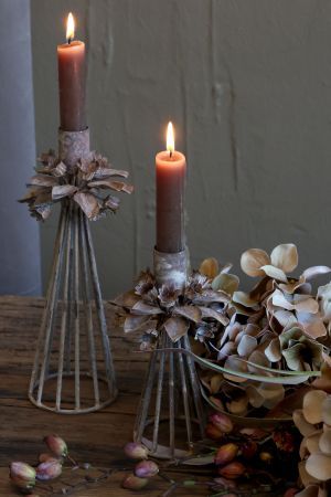 Rustic metal candle holder with a tapered cage base and decorative oak leaf wreath detail beneath the candle socket.