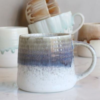 Ceramic mug with a softly rounded shape, curved handle and reactive glaze fading from earthy olive through smoky blue.