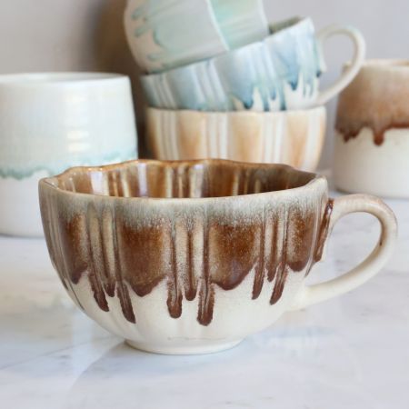 Slow Morning Cup in Toffee Melt, featuring a cream ceramic base, warm caramel-brown dripping glaze, ribbed texture, uneven ri
