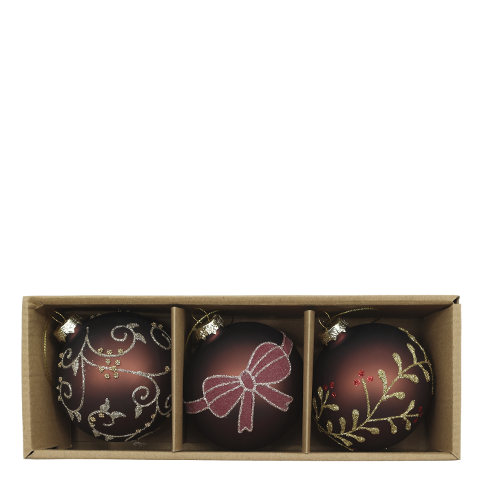 Three mocha Christmas baubles decorated with glittering bows, botanical sprigs and scrolls, arranged among evergreen foliage.