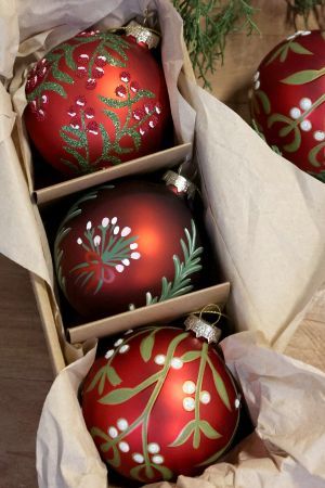 Boxed set of three red hand-painted Christmas baubles decorated with winter berries, foliage and a festive bird.