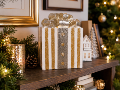 Light-up Christmas present decoration with gold and white stripes, a silver ribbon and a large glittering bow.