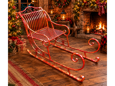 Giant red metal Christmas sleigh with sweeping runners, ornate scrollwork and snowflake details, displayed on grass.