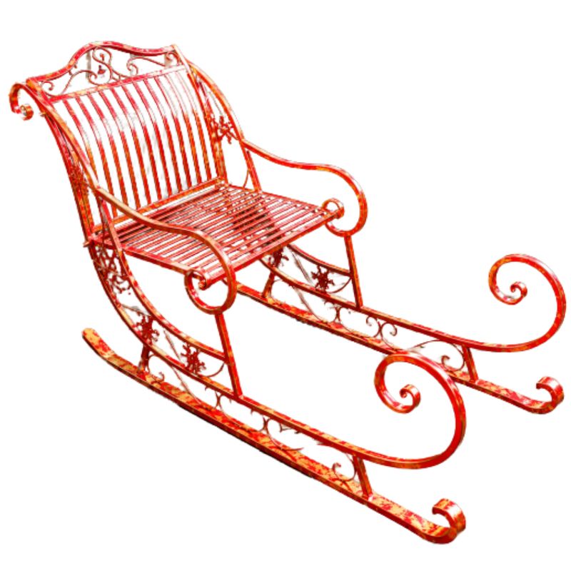 Giant red metal Christmas sleigh with sweeping runners, ornate scrollwork and snowflake details, displayed on grass.