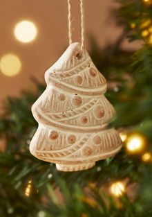 Four terracotta Christmas decorations shaped as a bauble, snowflake, dove and tree, with whitewashed carved patterns.