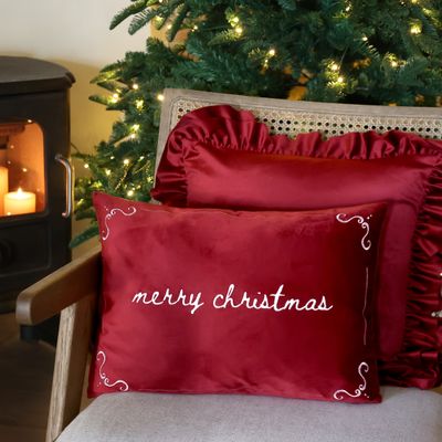 Scarlet rectangular cushion embroidered with ‘Merry Christmas’ in cream script and decorative scrolls in each corner.