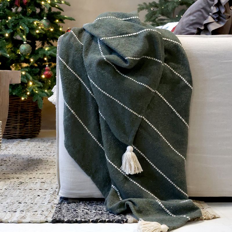 Deep evergreen woven throw with raised ivory stripes and large cream tassels at the corners.

