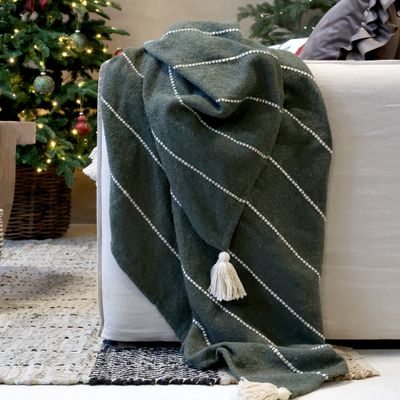 Deep evergreen woven throw with raised ivory stripes and large cream tassels at the corners.