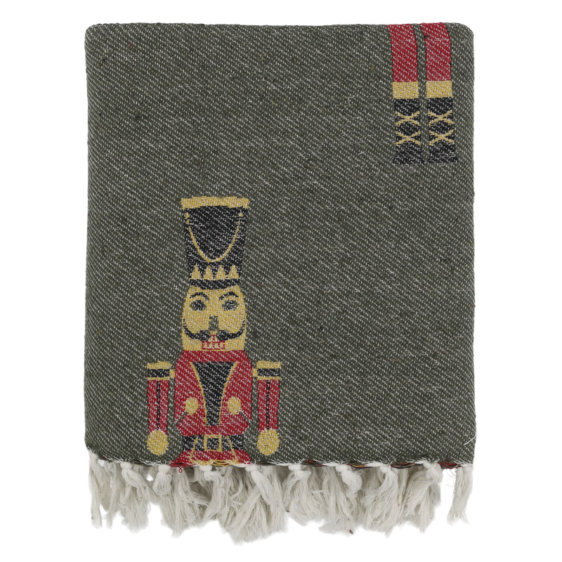 Forest-green woven Christmas throw with red nutcracker guards and an ivory knotted fringe.
