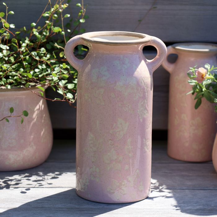 A rounded blush-pink ceramic jug with a curved handle, pouring lip & mottled glaze revealing a faint ivy pattern vase