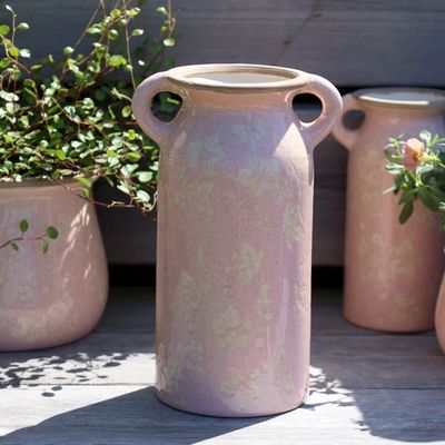 A rounded blush-pink ceramic jug with a curved handle, pouring lip & mottled glaze revealing a faint ivy pattern vase