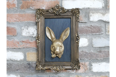 Ornate antique-style frame with a gold hare portrait on a deep blue background.