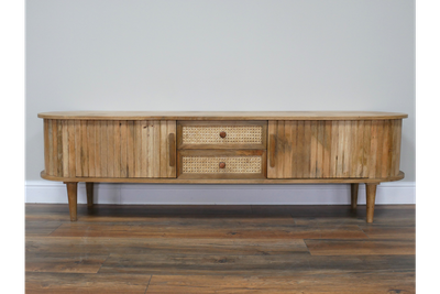 Low wooden TV cabinet with curved ends, fluted doors, two cane-fronted drawers and tapered legs.
