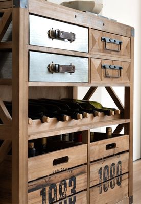 Natural wood wine cabinet on castors with bottle rack, mixed metal and geometric drawers, and two large crate-style drawers.
