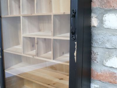 Vintage-style display cabinet with a distressed black frame, glazed front and natural wood shelves in varied sizes.