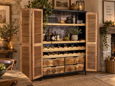 Wooden drinks cabinet with louvred doors, open shelving, wine racks, geometric drawers and black metal details.