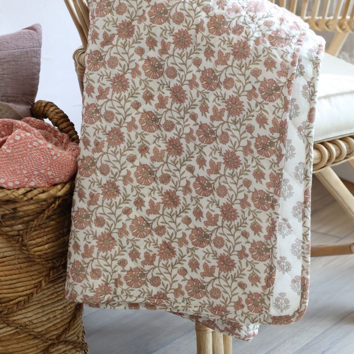 Reversible floral quilt in soft mocca tones on a melon background, with delicate sprig pattern and quilted stitching.