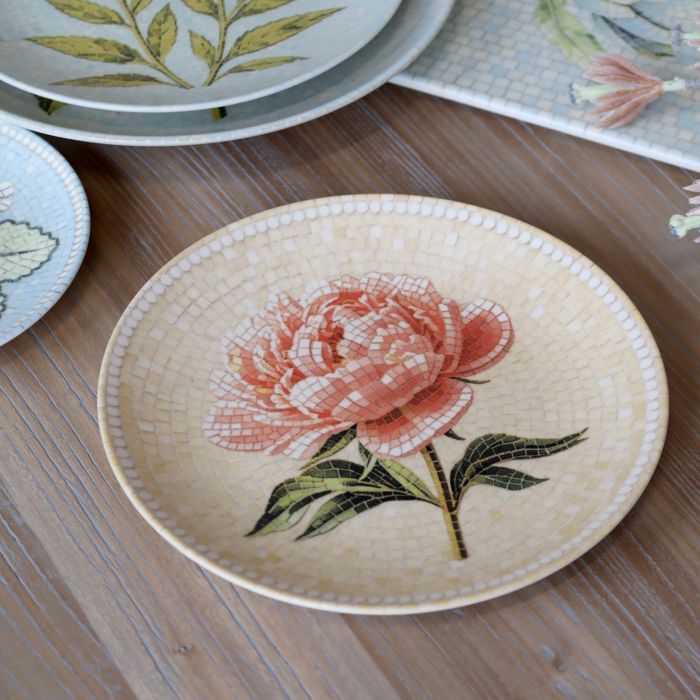 Round Chartres mosaic tray with a blush pink peony, dark green leaves, cream and yellow tiles and a white beaded border.
