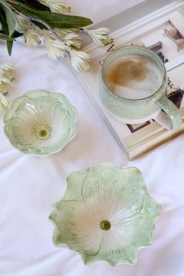Sage green ceramic flower bowl with softly curved petals, delicate raised stamens and a glossy white centre.