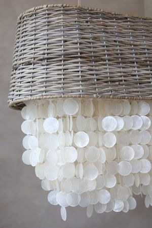 Coastal chandelier with a natural woven rattan drum shade and cascading layers of pearly white seashell discs.