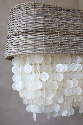 Coastal chandelier with a natural woven rattan drum shade and cascading layers of pearly white seashell discs.
