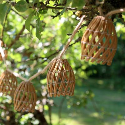 Rustic woven willow hanging garden decorations with tapered open latticework, suspended by natural rope from tree branches.