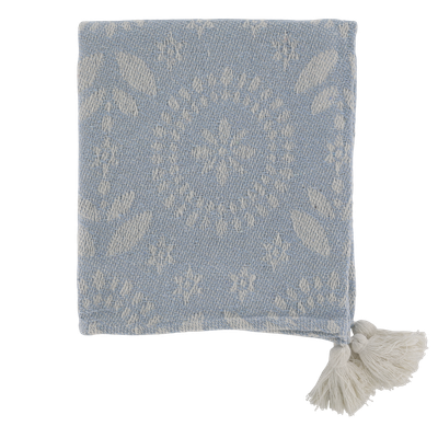 Soft blue woven throw with delicate ivory floral detailing, textured finish and decorative cream tassels at the corners.