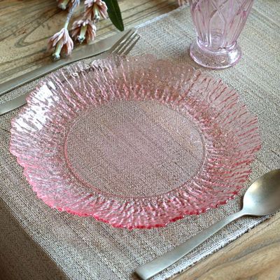 Blush pink decorative glass plate with a smooth circular centre, intricate rippled border and softly scalloped edges.