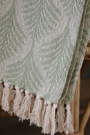 Soft sage green woven throw featuring an elegant ivory herringbone leaf pattern, textured finish and cream fringed edging.