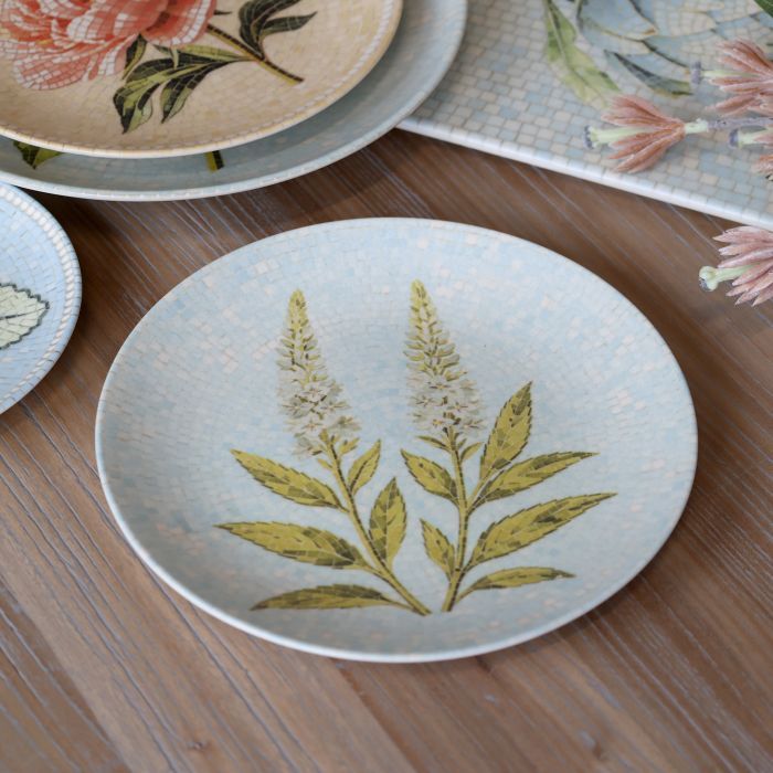 Round Chartres mosaic tray with two white flower spikes, olive green leaves and a pale blue and cream tiled background.