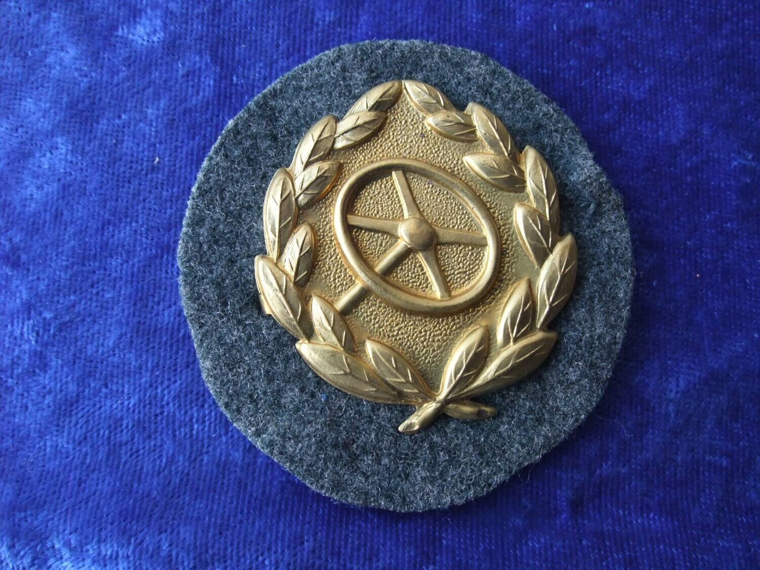 Kraftfahrbewährungsabzeichen in Gold auf feldgrauer Tuchunterlage mit Rückenplatte und Papierabdeckung
