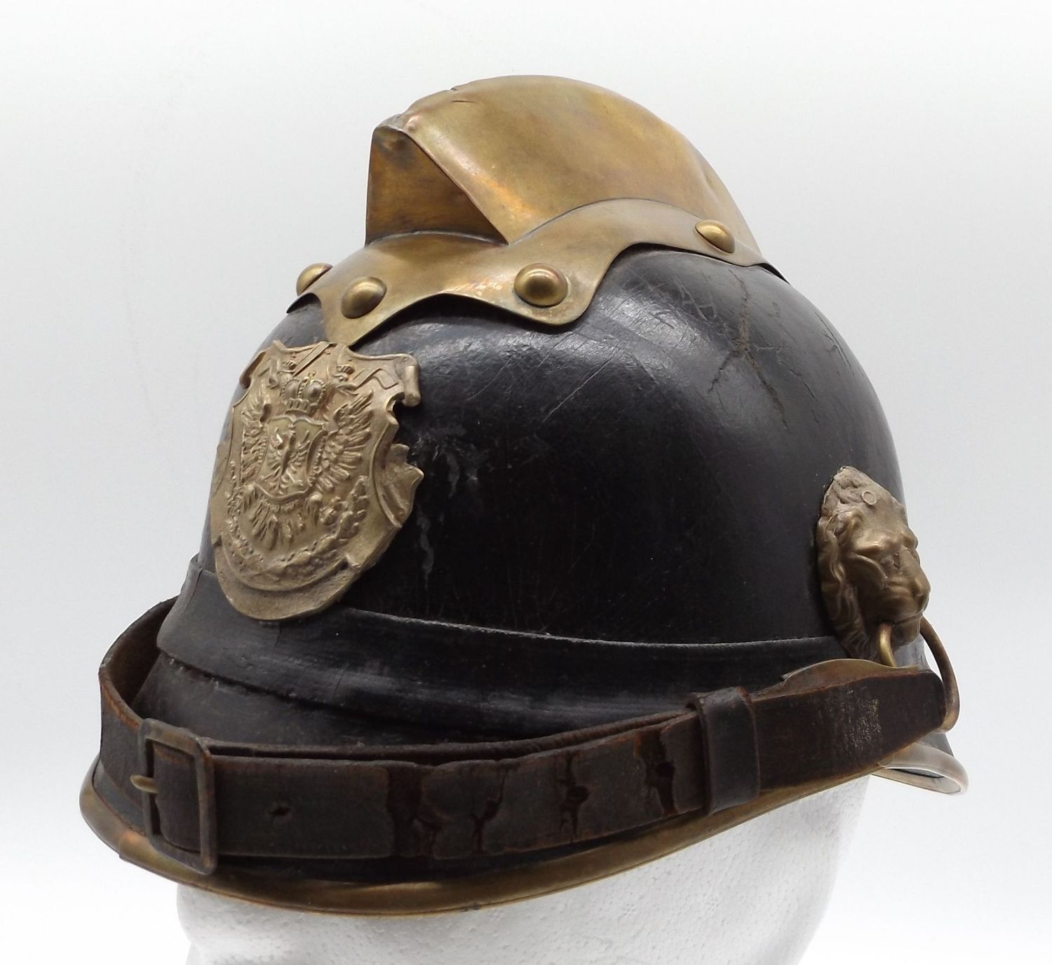 Österreich: K.u.K. Feuerwehr-Helm, Lederglocke, aufgelegtes Emblem, Kinnriemen an Löwenköpfen.