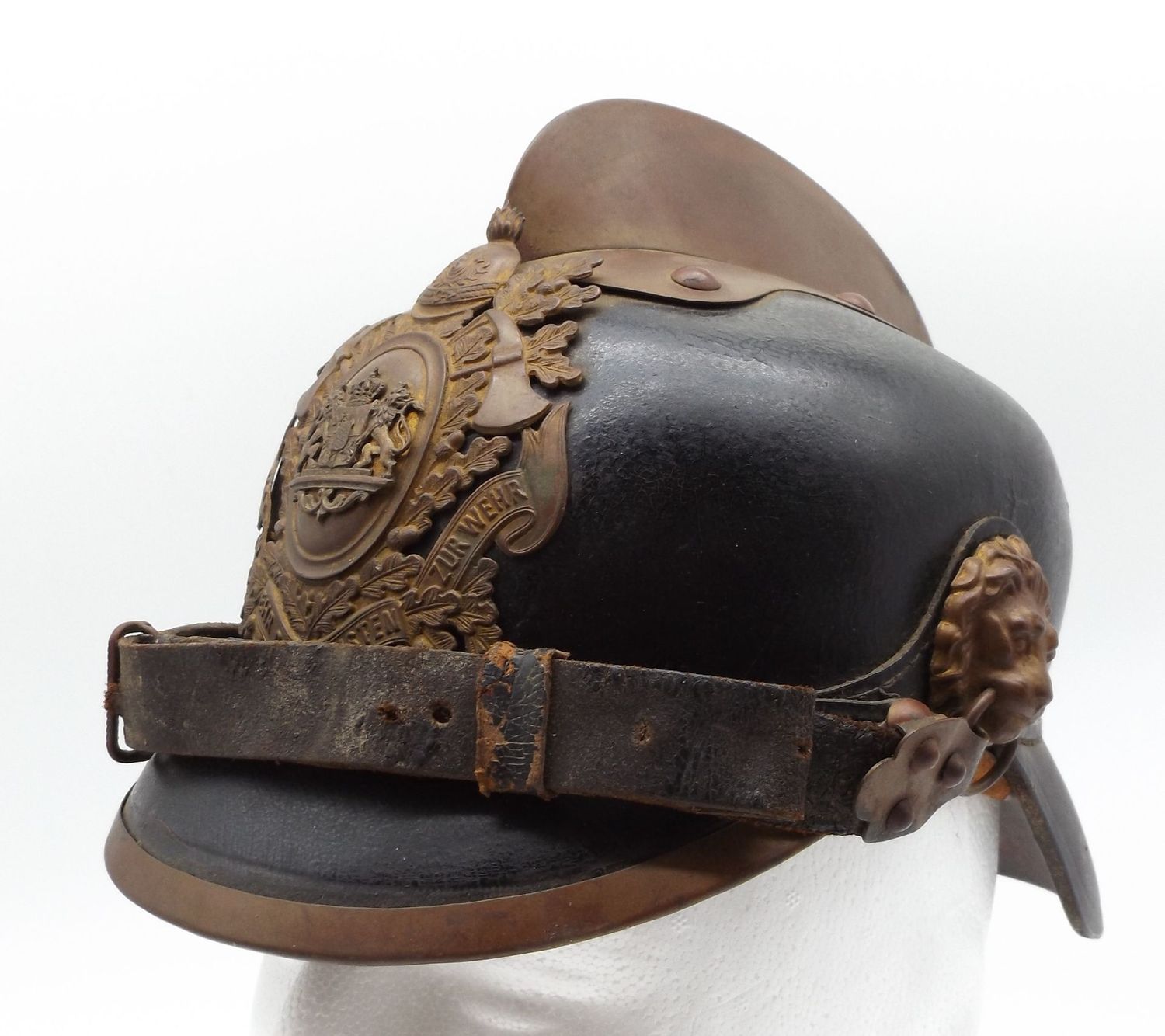 Bayern: Feuerwehr-Helm, Lederglocke, aufgelegtes Emblem, Kinnriemen an Löwenköpfen, Innenfutter, Reste des Herstelleretiketts.
