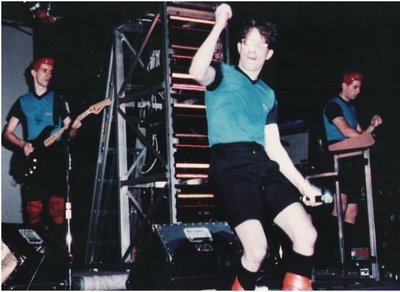 Devo / On Stage, Mark in Center, Blue-Black Shirts | 1981