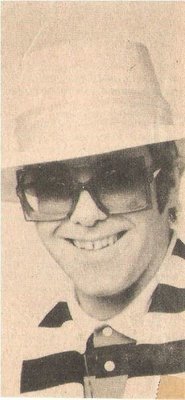 John, Elton / Closeup, Smiling, Light Color Hat, Striped Shirt (1976)