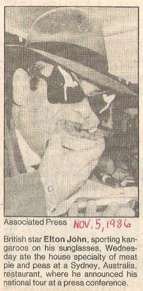 John, Elton / Eating Meat Pie and Peas in Australia | Newspaper Photo with Caption (1986)