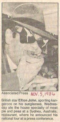 John, Elton / Eating Meat Pie and Peas in Australia | Newspaper Photo with Caption (1986)